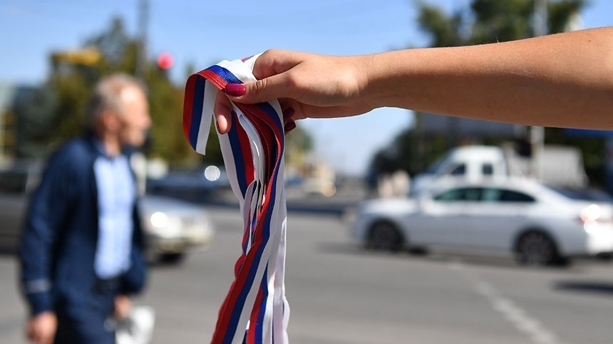 Волонтер движения "Мы вместе" раздает ленточки триколора в рамках подготовки к референдуму о присоединении к России.