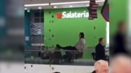 Девушка сидит на краю перил в торговом центре за секунду до падения— шокирующие кадры (18+)