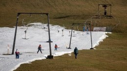 Лыжники катаются на зеленых склонах в Швейцарии