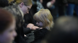 Маленькая дочь Романа Попова прижалась к матери на прощании с отцом