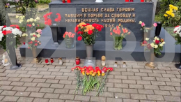Жители Риги несут цветы к памятнику советским солдатам на Покровском кладбище